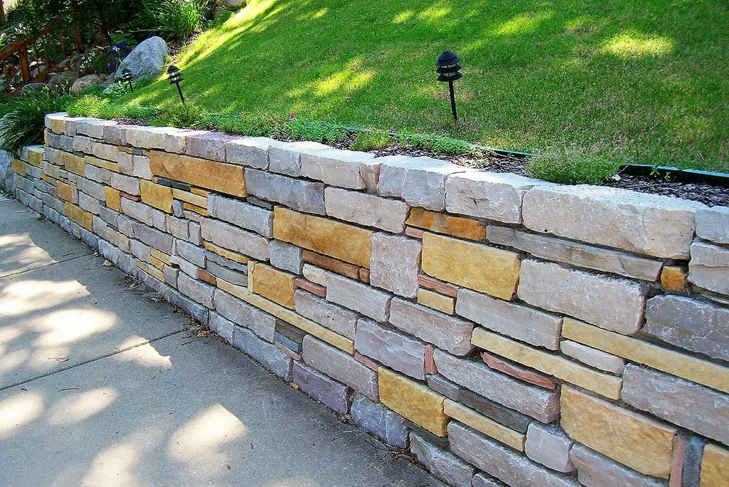 Weeping tile and drainage aggregate being installed behind an excavated retaining wall section.